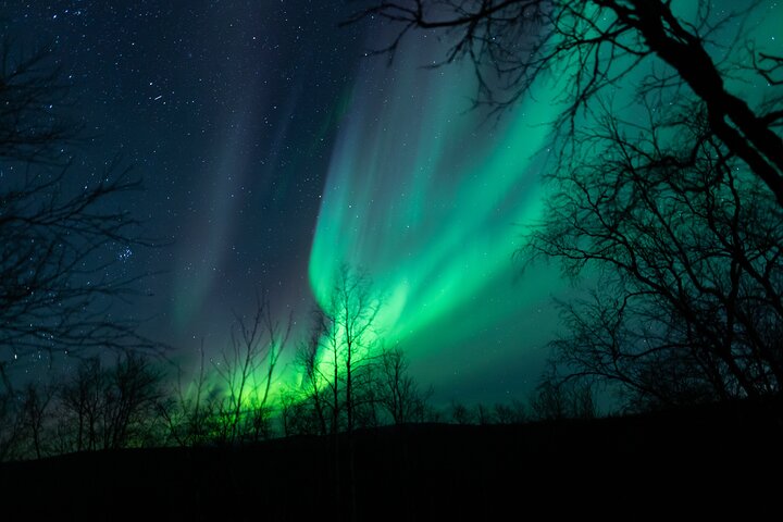 The Aurora Borealis illuminating a snowy Norwegian fjord.